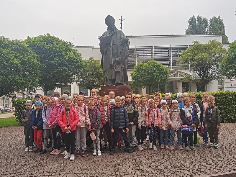 dzieci stoja przy pomniku Jana Pawła II w Wieluniu